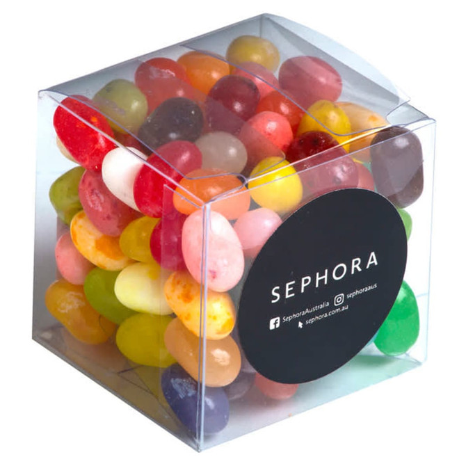 A clear cube filled with colourful jelly beans, featuring various vibrant flavours. The packaging includes a logo.