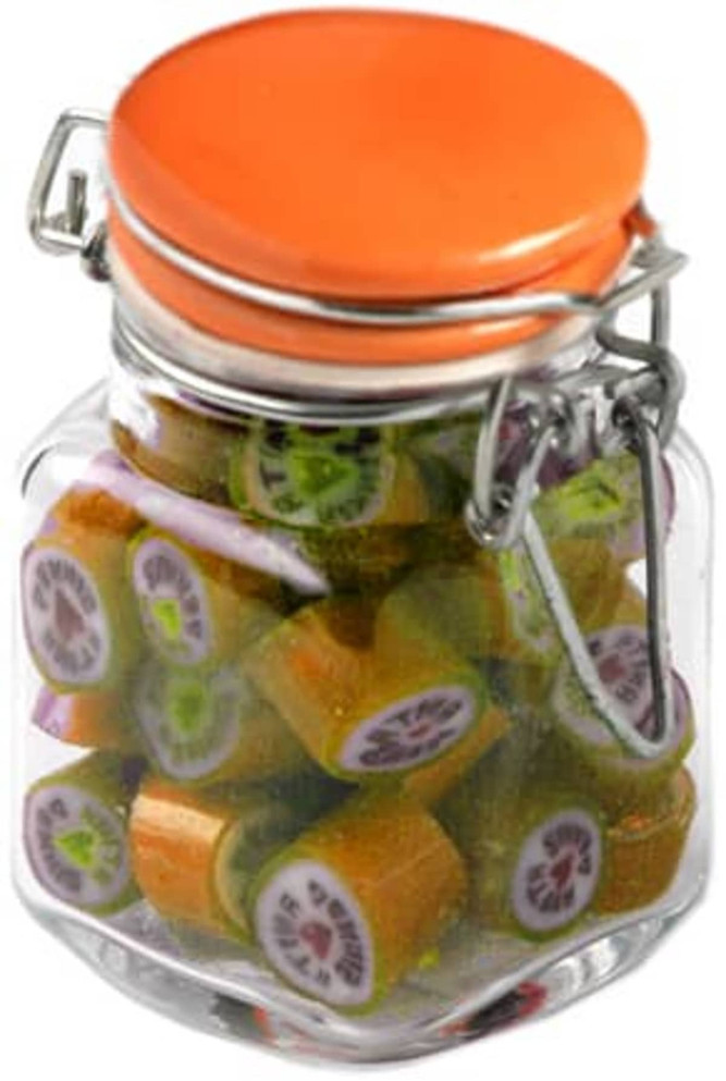 A glass jar with an orange lid filled with colourful rock candy pieces in various shapes. The jar has a metal clasp.
