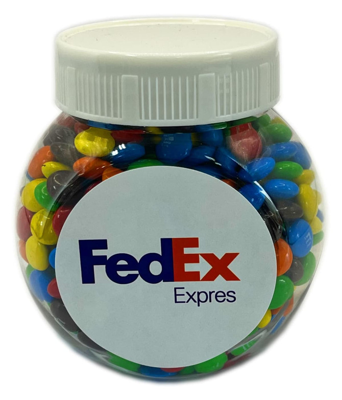A plastic jar filled with multicoloured M&Ms, featuring a logo on the front.