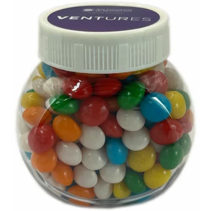 A plastic jar filled with colourful chewy fruit sweets in various shades, including red, green, yellow, blue, and white.