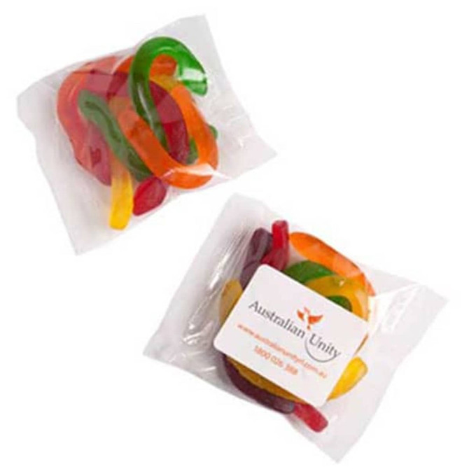 A clear plastic bag contains colourful gummy snakes in red, green, yellow, and orange hues, featuring a logo on the packaging.