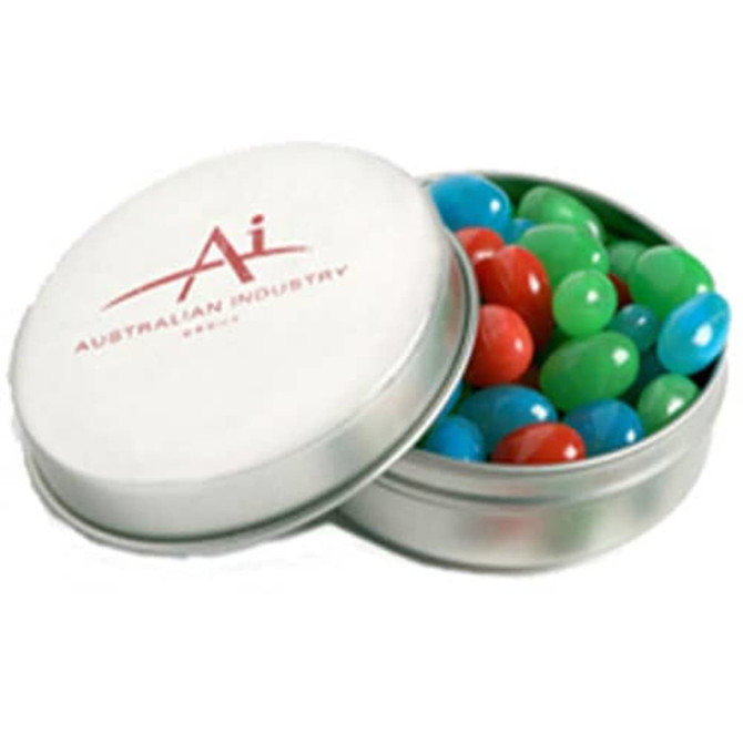 A metal tin with a white lid contains colourful jelly beans in red, green, and blue. The tin has a logo.