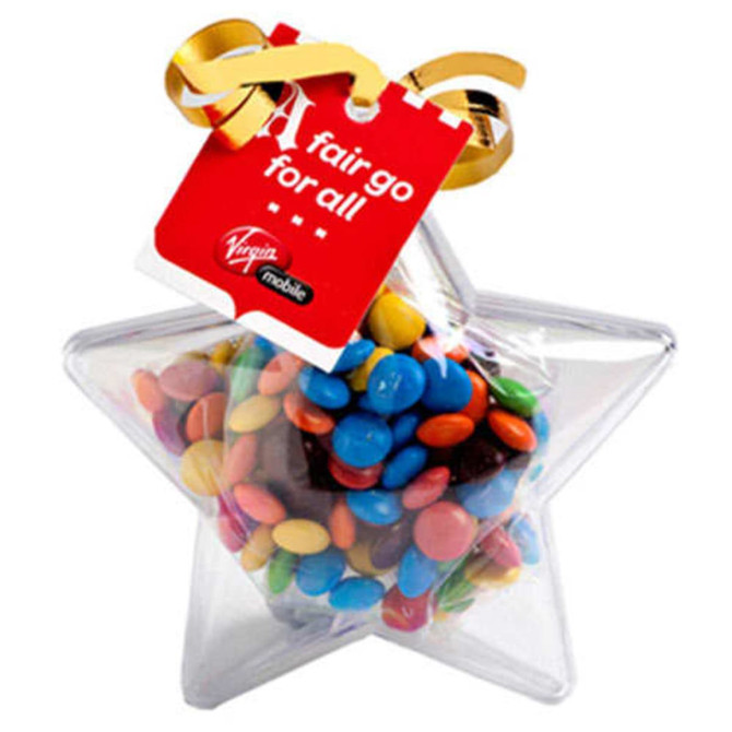 A clear acrylic star filled with colourful M&Ms, topped with a ribbon and a tag.