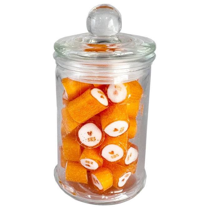 A glass apothecary jar filled with orange rock candy pieces, featuring a clear lid.