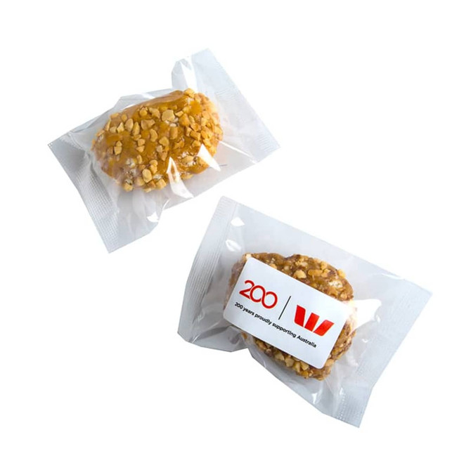 Two individually wrapped protein balls coated in crushed nuts, featuring a simple logo on the packaging.