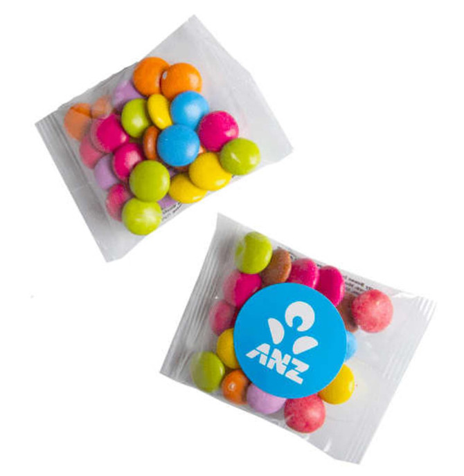 A packet of Smarties containing colourful candy in shades of pink, blue, yellow, orange, and green, with a logo.