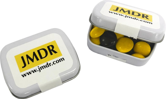 A small rectangular tin containing yellow and black choc beans, with a logo on the lid.