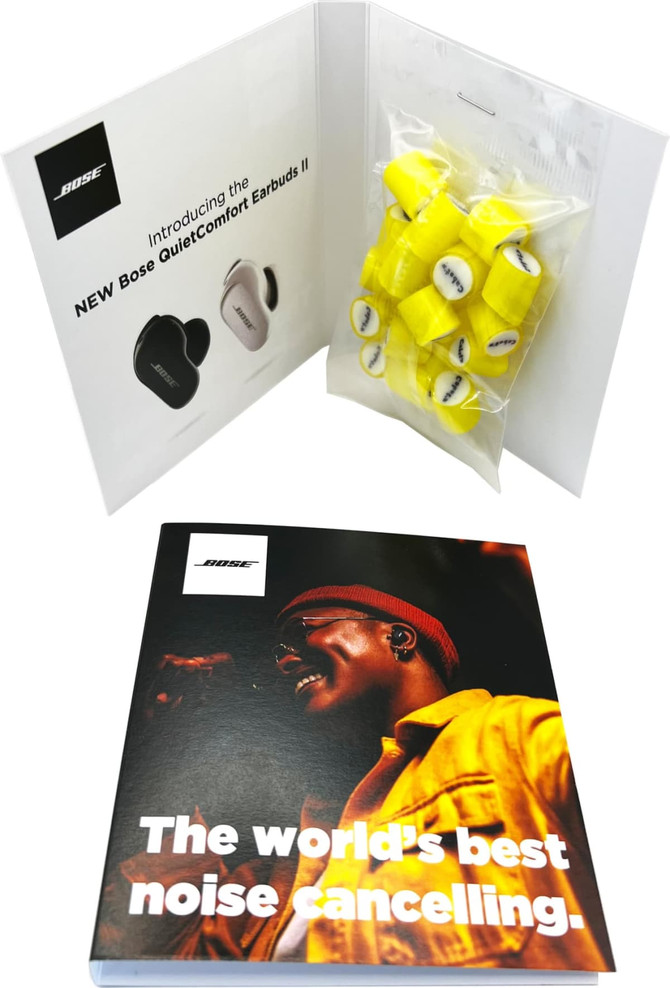 A product display featuring Bose QuietComfort Earbuds II in white and black, with yellow ear tips packaged alongside.