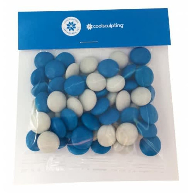 A clear bag filled with blue and white chocolate-coated beans, featuring a logo at the top.