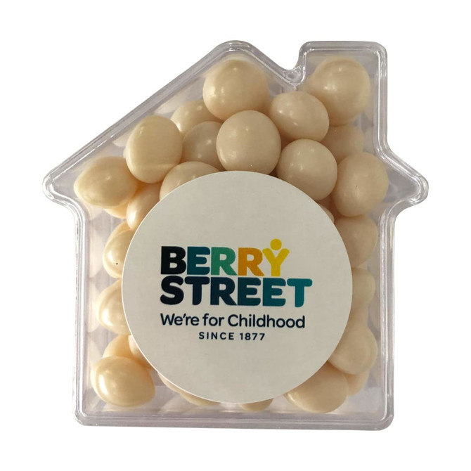 A clear acrylic house-shaped container filled with white mints, featuring a circular logo on the front.