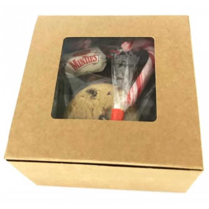 A small kraft gift box containing a cookie, a candy cane, and a branded treat, in a natural brown colour.