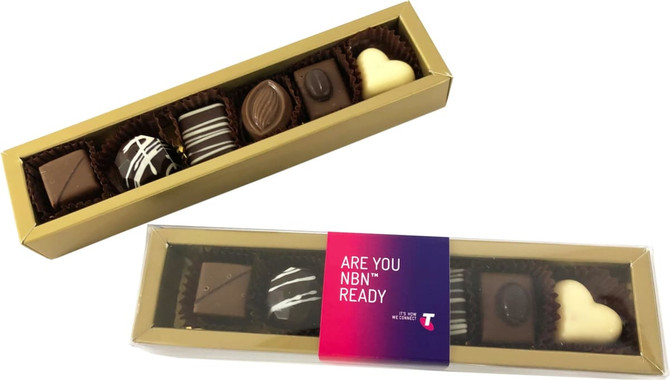 A gold box containing assorted pralines, including dark, milk, and white chocolates, with decorative patterns.