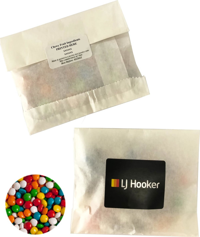 A kraft paper bag containing chewy fruit confectionery, featuring an assortment of vibrant colours. The bag has a logo.