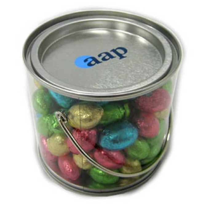 A medium silver bucket filled with colourful mini Easter eggs in gold, green, pink, and blue, featuring a logo on the lid.