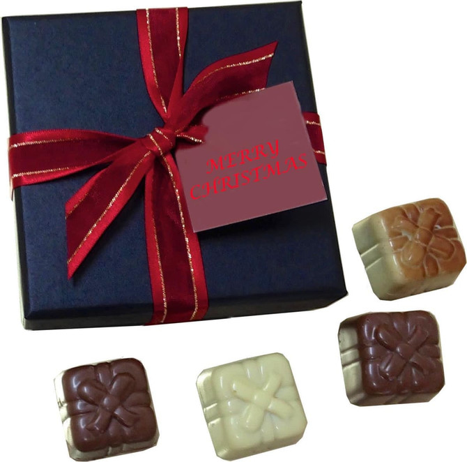 A dark blue gift box tied with a red ribbon containing four different chocolates in various colours.