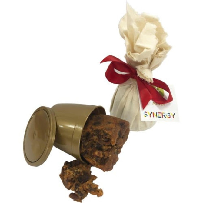 A gold container spilling a rich, dark brown Christmas pudding, wrapped in cream fabric and tied with a red ribbon.