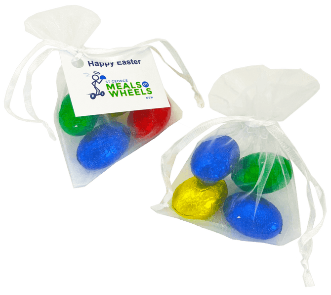 Organza bags containing four mini solid Easter eggs in blue, green, and gold. Each bag is tied with a white ribbon.