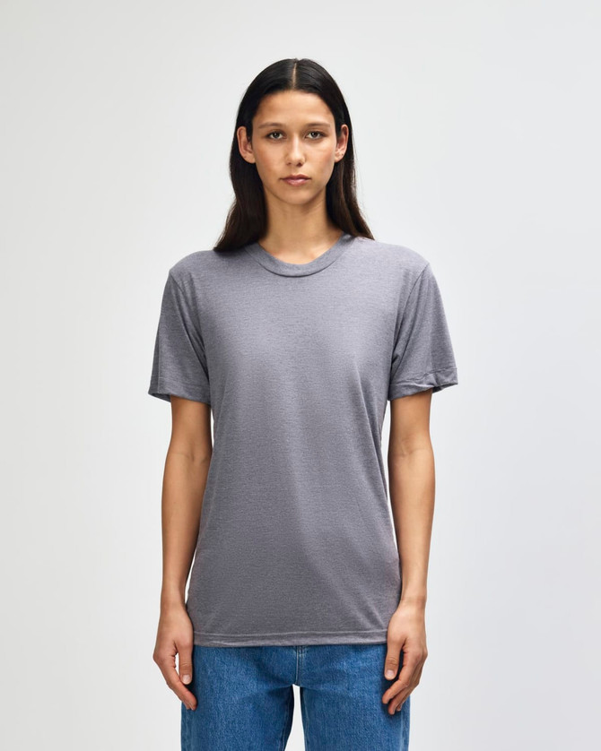 A grey American Apparel tri-blend T-shirt on a model, featuring short sleeves and a round neckline.
