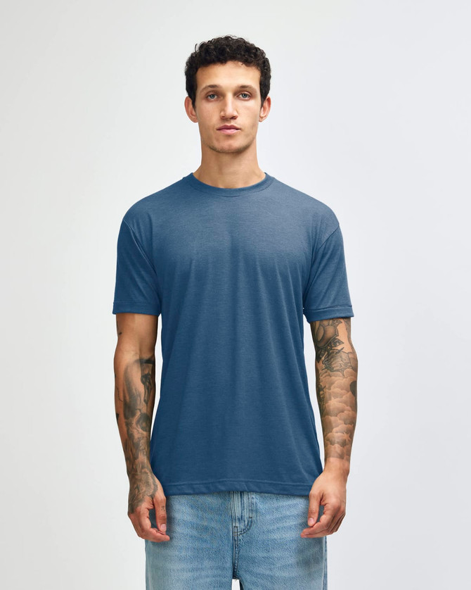 A blue American Apparel tri-blend T-shirt displayed on a model with tattoos, paired with denim jeans.