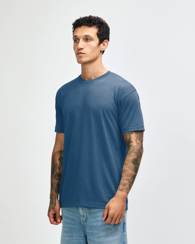 A blue tri-blend t-shirt displayed on a model with tattoos, featuring a simple design and no visible logos.