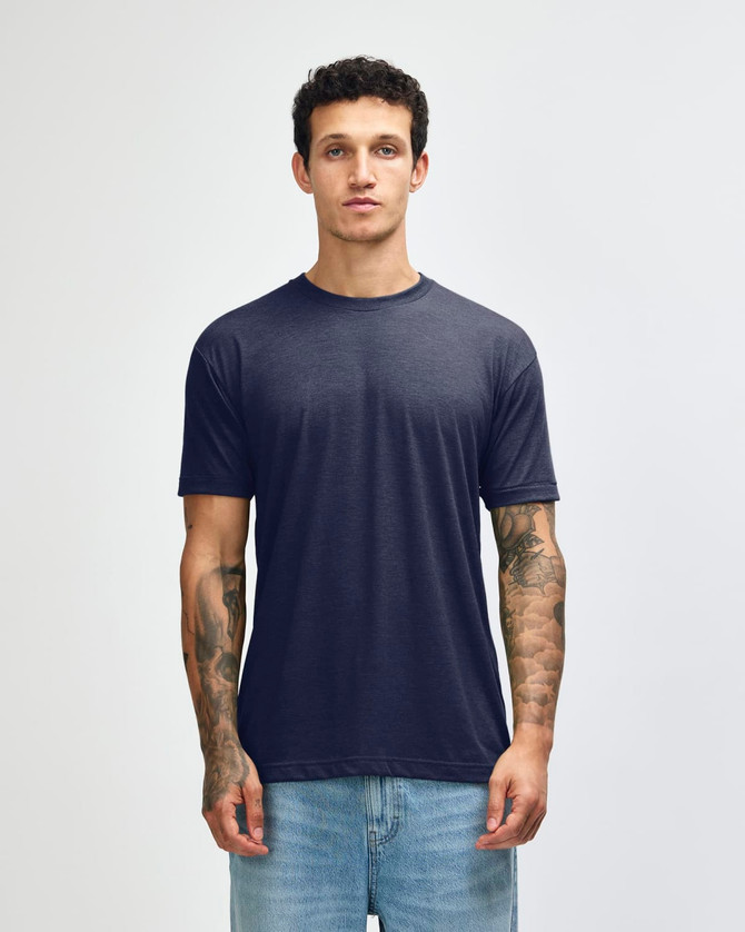 A navy American Apparel tri-blend T-shirt displayed on a model with tattoos, paired with light blue jeans.