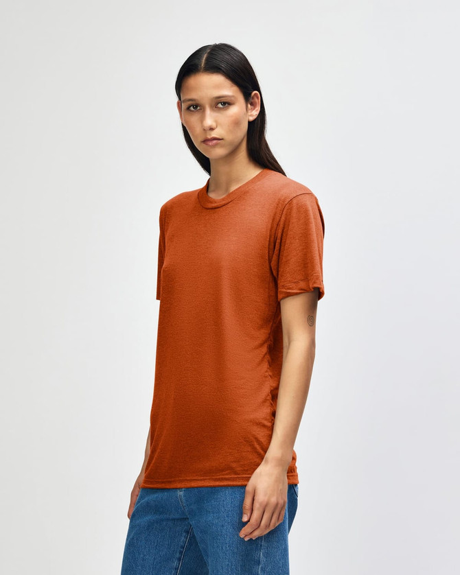 A model wearing an orange American Apparel Tri-Blend T-Shirt, styled with blue jeans, displaying a casual look.