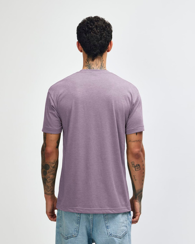 A tri-blend t-shirt in a muted purple colour, viewed from the back, worn by a person with tattoos.