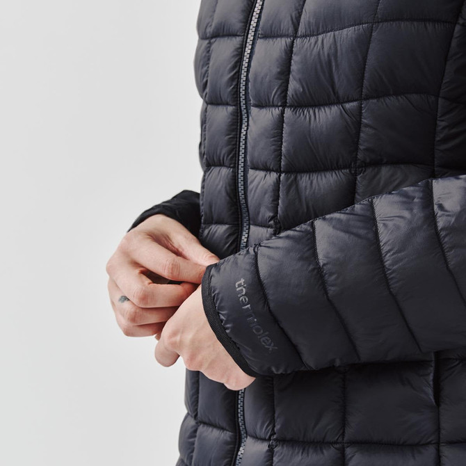 A women's puffer jacket in black, featuring a quilted design and a close-up of the cuff with a logo.