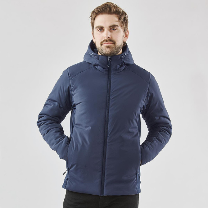 A man wearing a navy puffer jacket with a hood, featuring a branding logo. The jacket has a sleek, modern design.