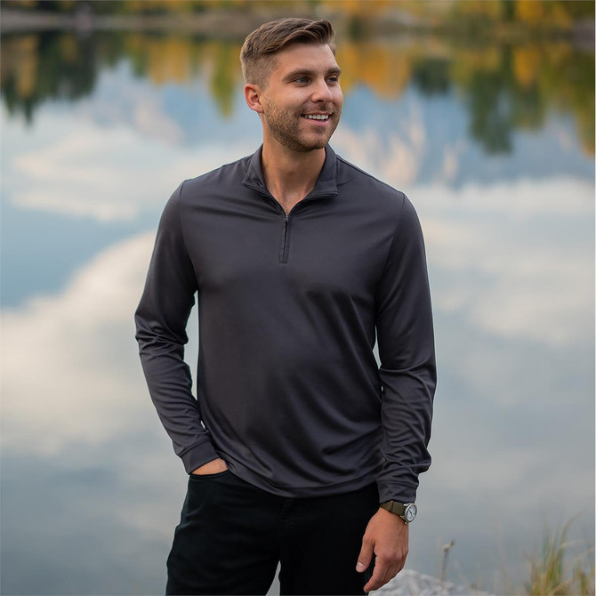 A men's charcoal grey 1/4 zip pullover in a scenic outdoor setting by a body of water.