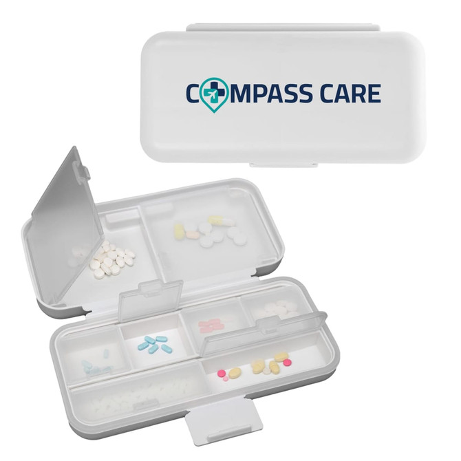 A white compact pill organiser with multiple compartments, featuring a logo on the lid and various coloured pills inside.