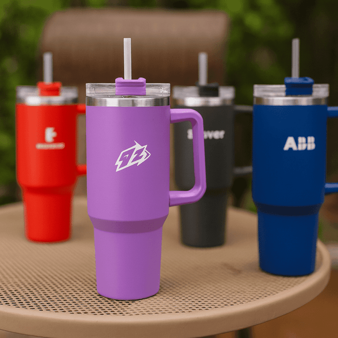 A drink bottle with a purple body and a transparent lid, featuring a straw, alongside red, black, and blue bottles, each with a logo.