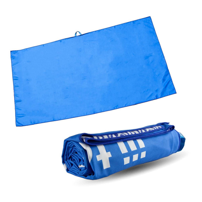 A blue suede fabric sand-free beach towel, displayed laid out flat and rolled up. The product has a branding logo.