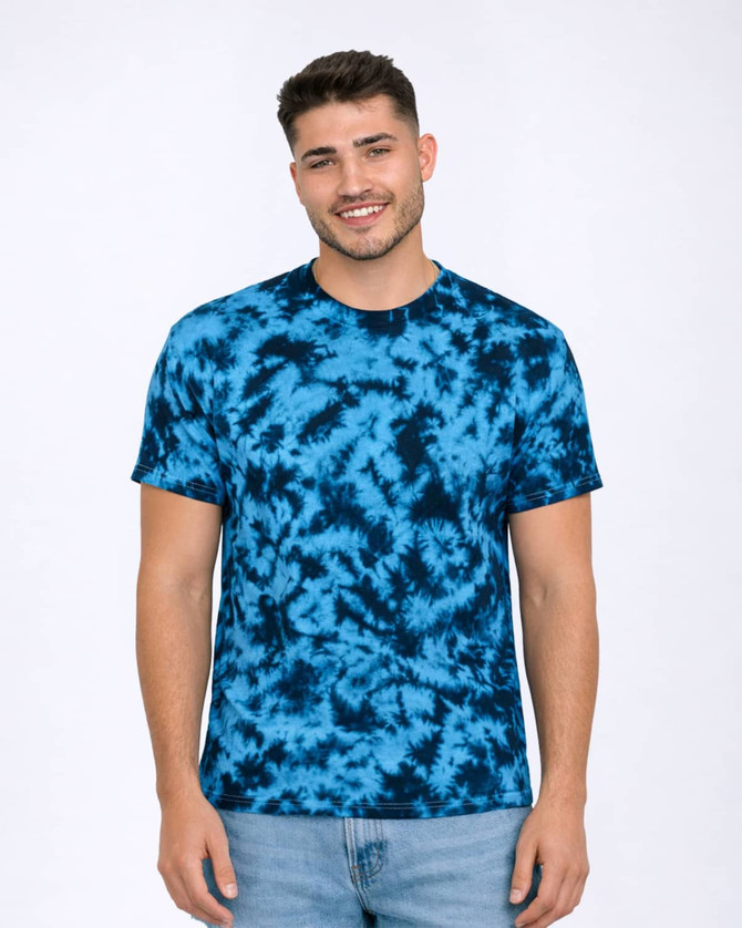 A tie-dye T-shirt in shades of blue, featuring a round neckline and short sleeves. The model is standing and smiling.