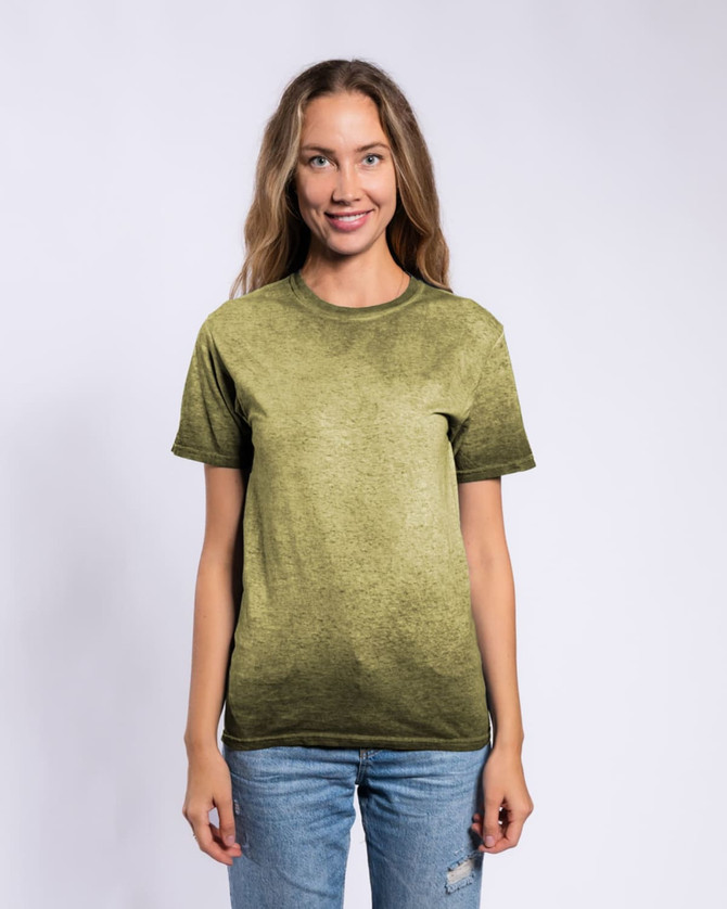 A woman wearing a green Colortone® Oil Wash T-Shirt, standing against a plain background. The shirt features a soft, textured finish.