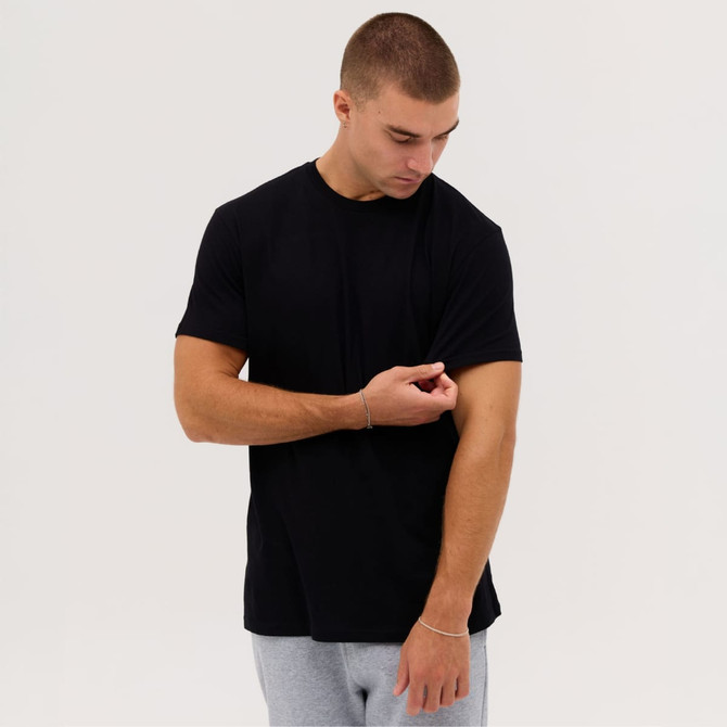 A black short-sleeve t-shirt is worn by a model adjusting the sleeve, set against a plain background.