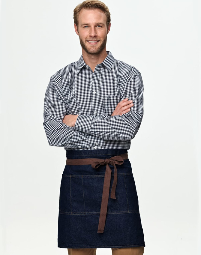 A man in a checkered shirt wears a denim half apron with a brown tie belt. The apron features pockets and a logo.