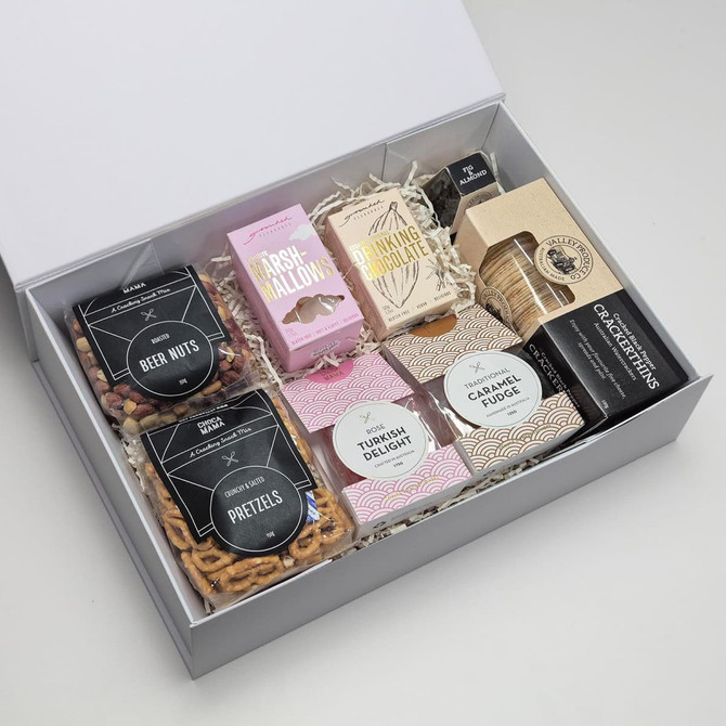 A gift box featuring an assortment of sweets and snacks, including pretzels, marshmallows, Turkish delight, and fudge.