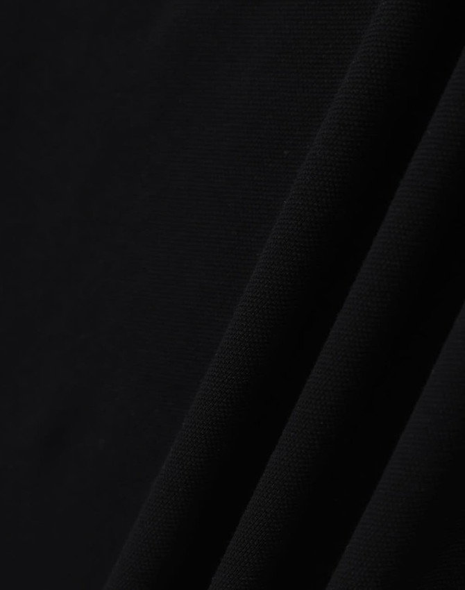 A close-up of black ultrafine cotton pique fabric, textured with a smooth finish. It features subtle folds.