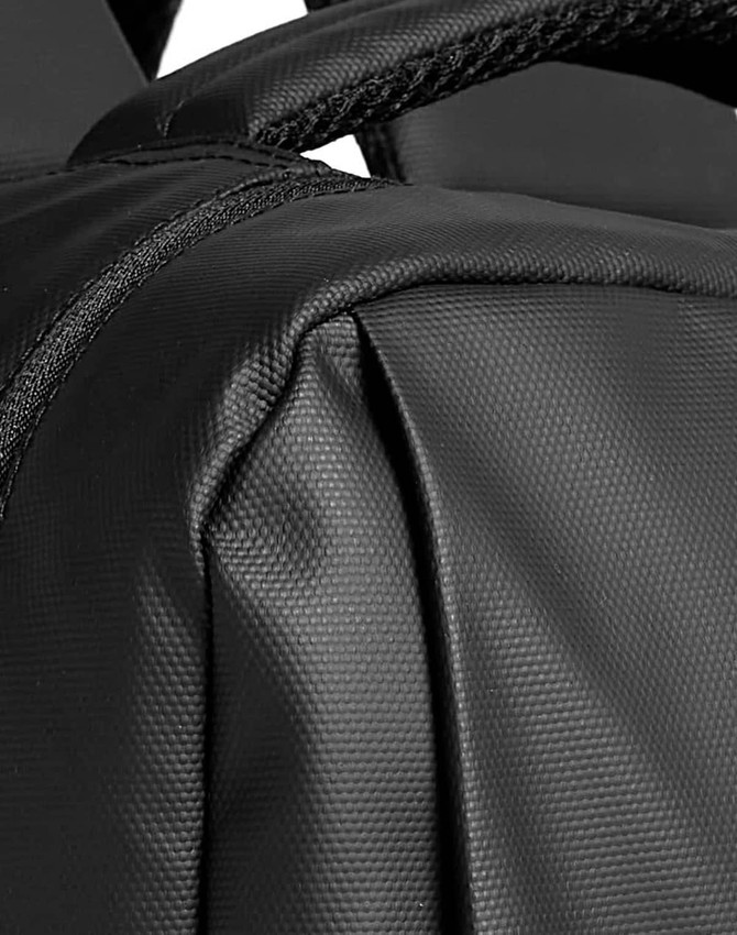 A close-up of a textured black backpack, featuring stitching and straps, with branding visible.
