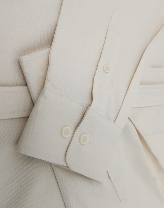 A men's smart casual long-sleeve shirt in a light cream colour, featuring buttoned cuffs and a soft cotton blend fabric.