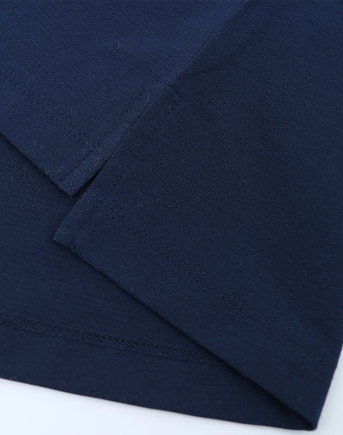 A close-up of navy blue fabric featuring stitched hems, showcasing the texture and quality of a polo shirt.