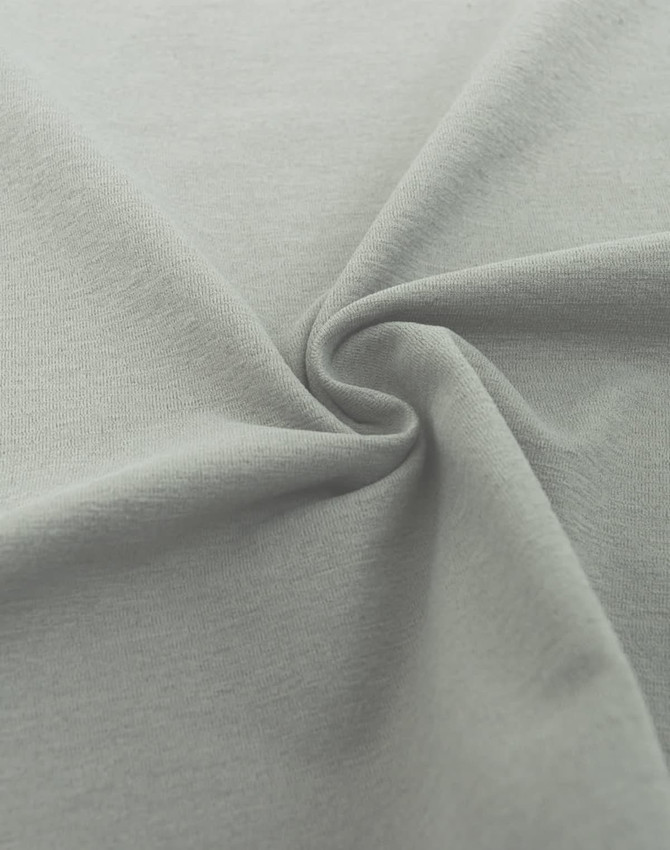 A close-up of a soft, grey fabric in a spiral formation, showcasing its smooth texture.