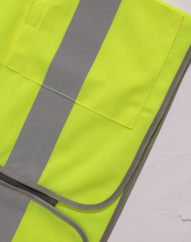 A bright yellow high-visibility safety vest featuring grey reflective stripes and utility pockets.