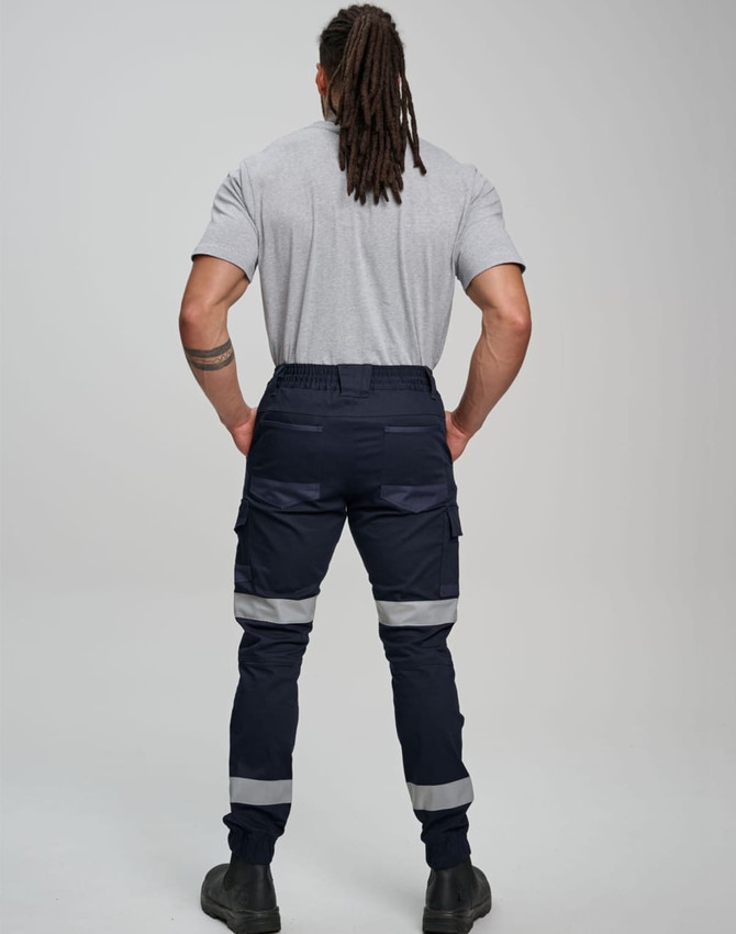 Cotton stretch drill cuffed work pants in navy with reflective tape, viewed from behind on a model.