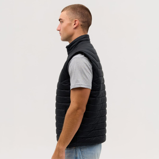 A man in a side profile wearing a black puffer vest over a grey t-shirt. The vest has a logo on it.