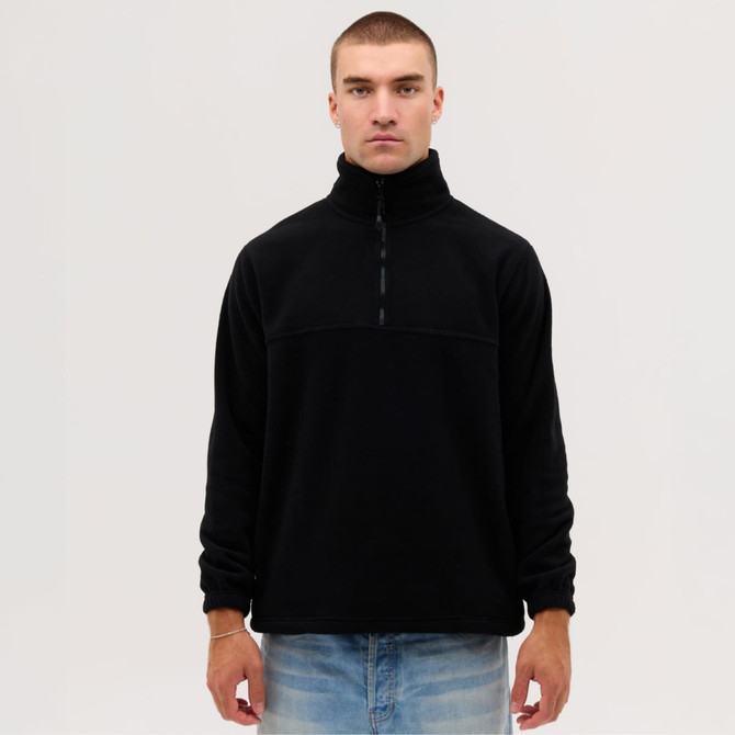 A black fleece 1/4 zip top on a model, featuring a high collar and long sleeves. There is a logo on the garment.