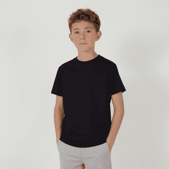 A youth essential tee in black, featuring a classic crew neck design. The model is standing with hands in pockets.