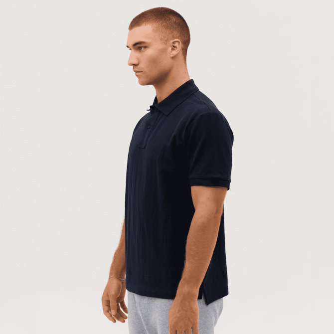 A navy polo shirt featuring a collar and short sleeves, displayed on a model from the side. The shirt has a logo.