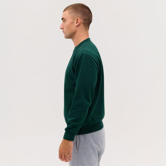 A green crew sweatshirt worn by a male model, paired with grey sweatpants, displayed from the side.